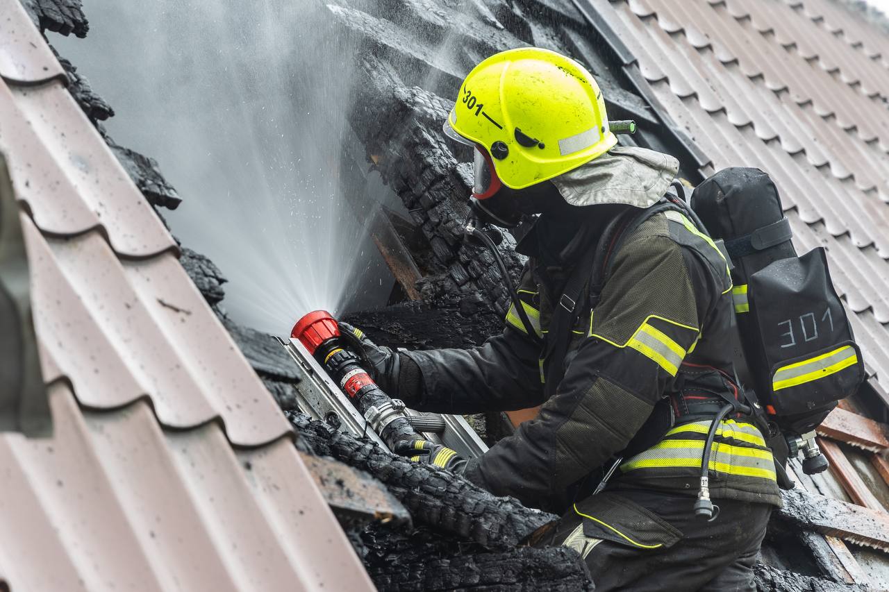 Пожарный тушит крышу дома